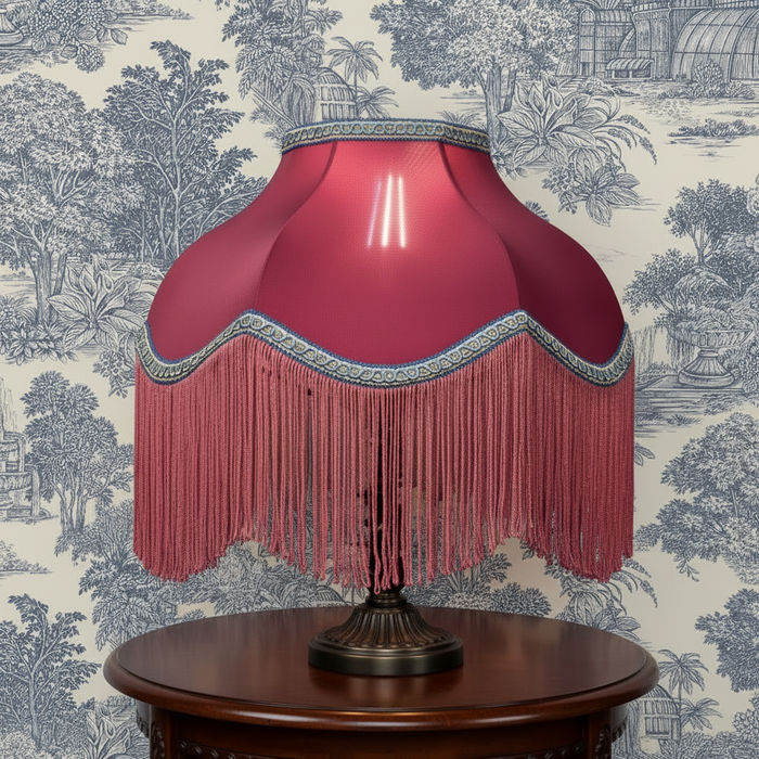 Pink lampshade with blue trim on table with blue toile wallpaper background