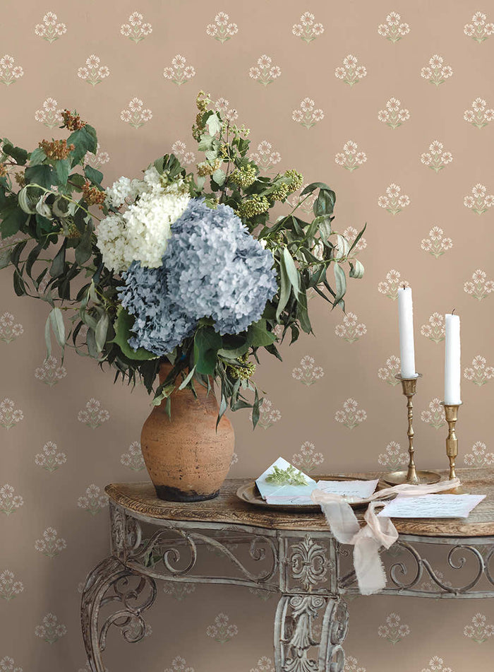 Plaster pink Isadora floral sprig wallpaper on a bedroom wall
