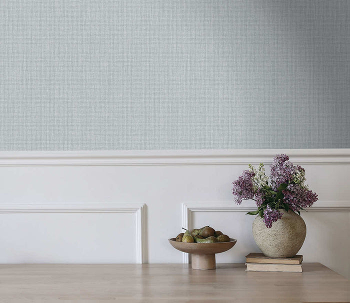 Pale blue Ormsby linen texture wallpaper on a bedroom wall