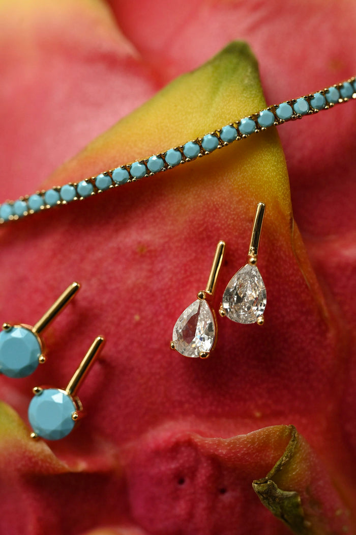 Gold earrings with gemstones on a red flower background